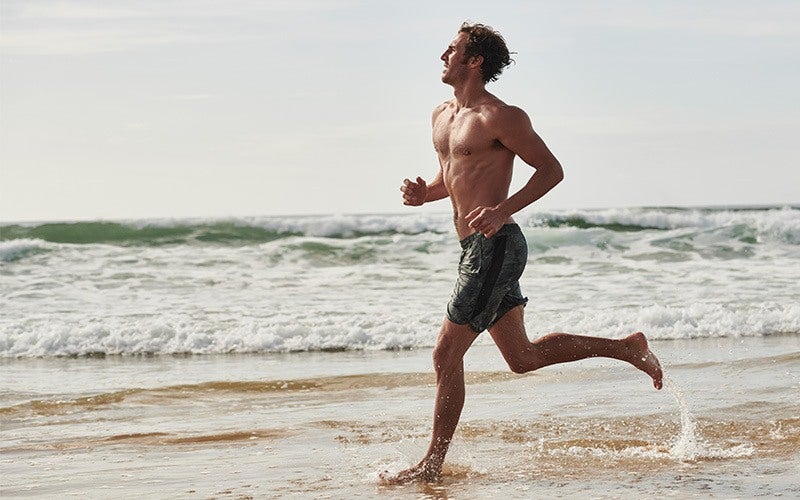 homme qui court le long de la plage pour garder la forme en vacances