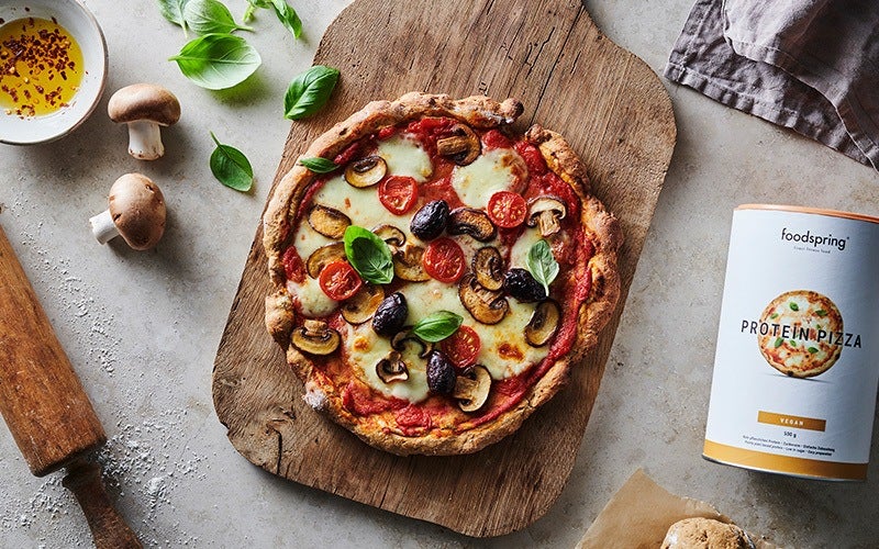 pizza proteica funghi, olive e pomodorini su un tagliere