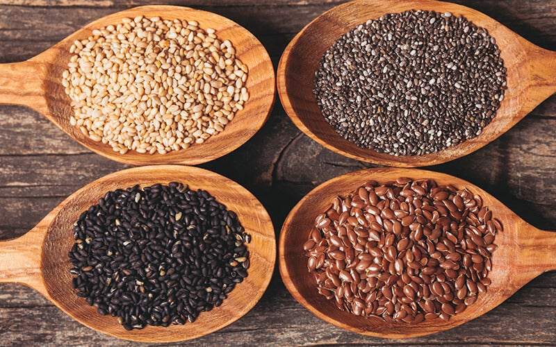 Vier Holzlöffel mit unterschiedlichen Saaten Samen