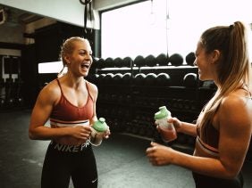 Zwei sportliche Frauen trinken Eiweiß-Shake
