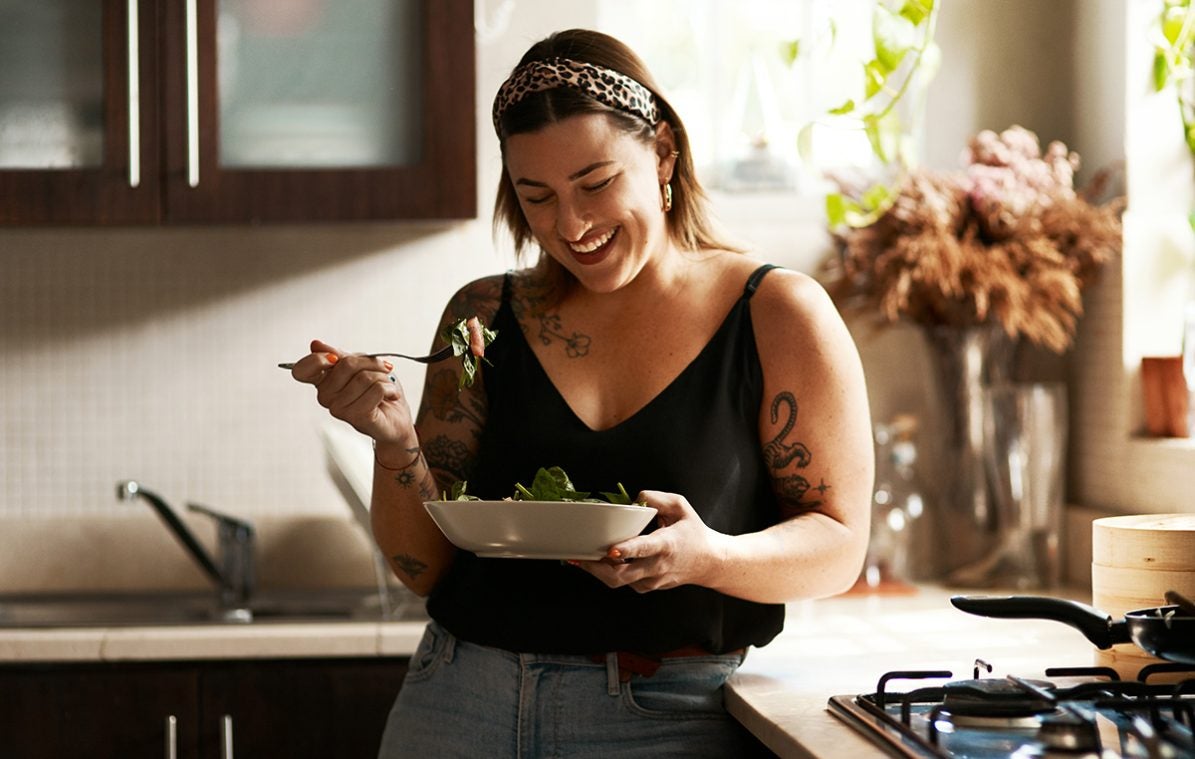Eine Frau isst Salat in der Küche