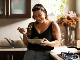 Eine Frau isst Salat in der Küche