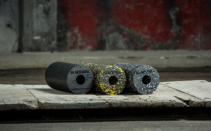 Three differently-colored foam rollers from BLACKROLL sit in a line.