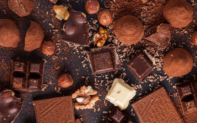 chocolate, spices, and nuts laid out on a black background seen from above. The WOOP method is one way to reduce your chocolate habit if you want.