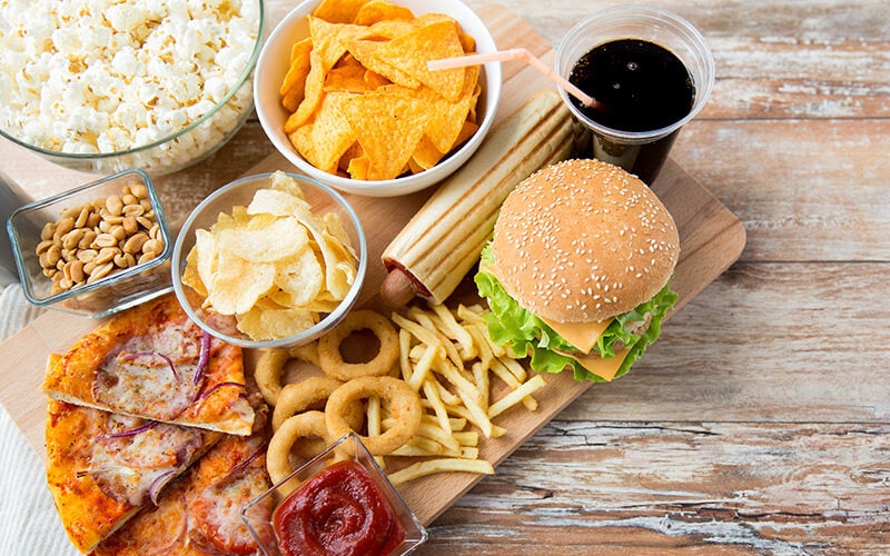 Ungesunde Fast-Food-Snacks und Getränke auf Tisch