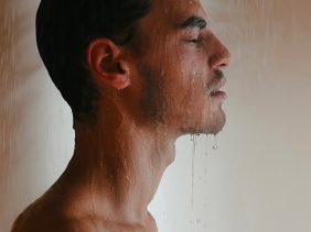 Mann steht unter einer kalten Dusche