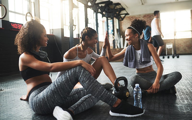 Frauen sitzen im Gym auf dem Boden und lachen