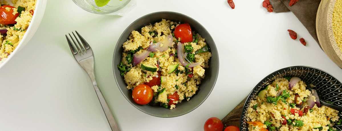 A bowl of couscous salad mixed with bright cherry tomatoes, red onions, zucchini, and vibrant green parsley is just one of many meal prep ideas