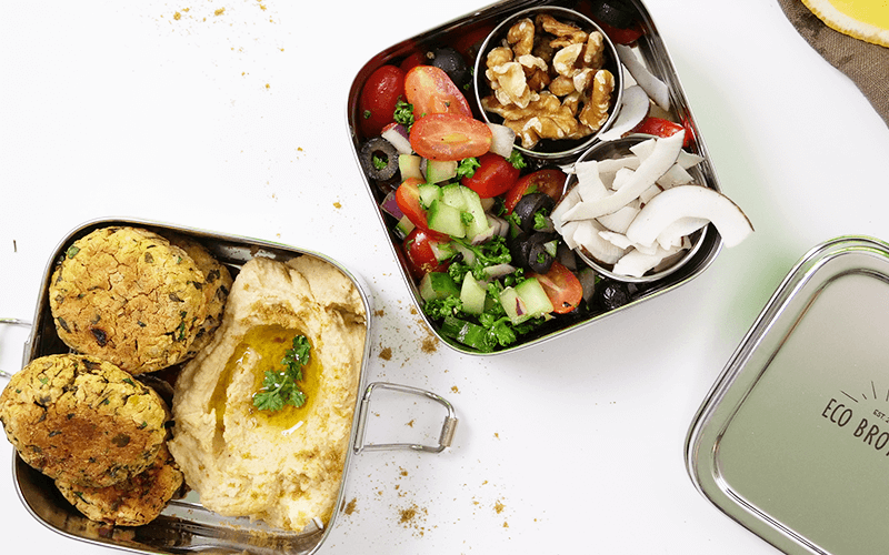 A stainless steel lunch box packed with hummus, falafel, and a tomato-cucumber salad is one of many fabulous meal prep ideas