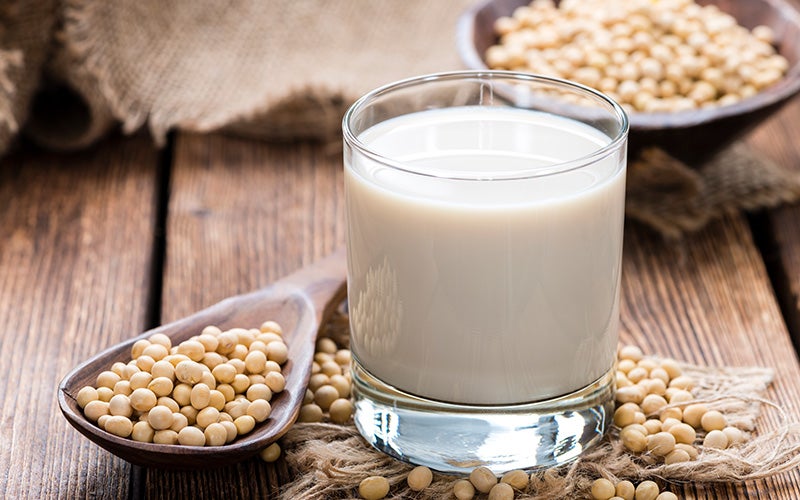 A glass of soy milk surrounded by soy beans