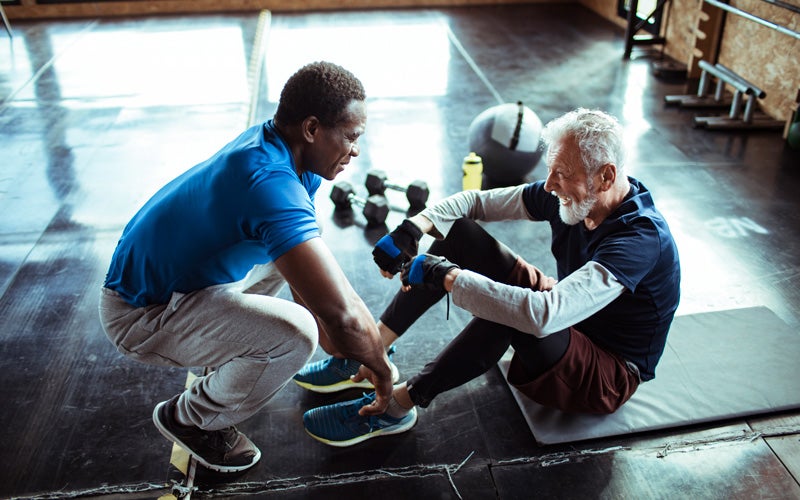 Ein älterer Mann macht Sit Ups mit einem Trainer