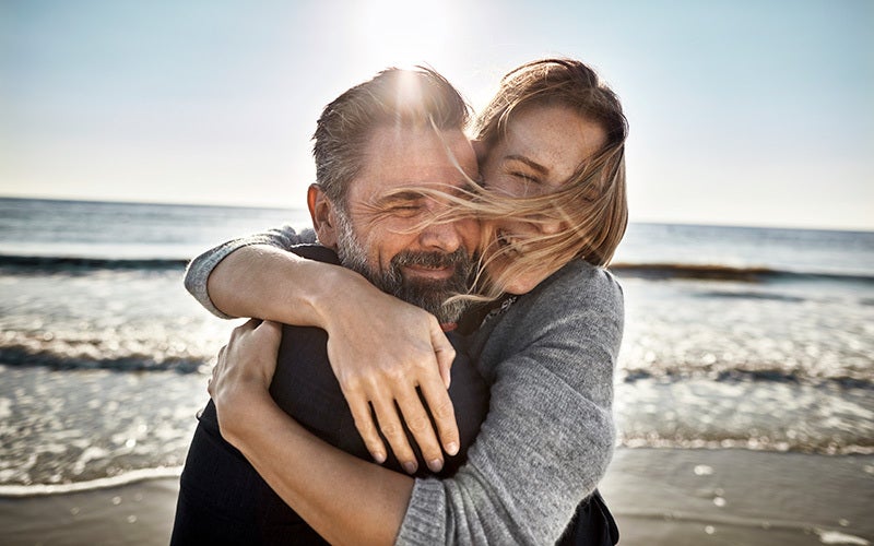 Mann und Frau umarmen sich am Strand