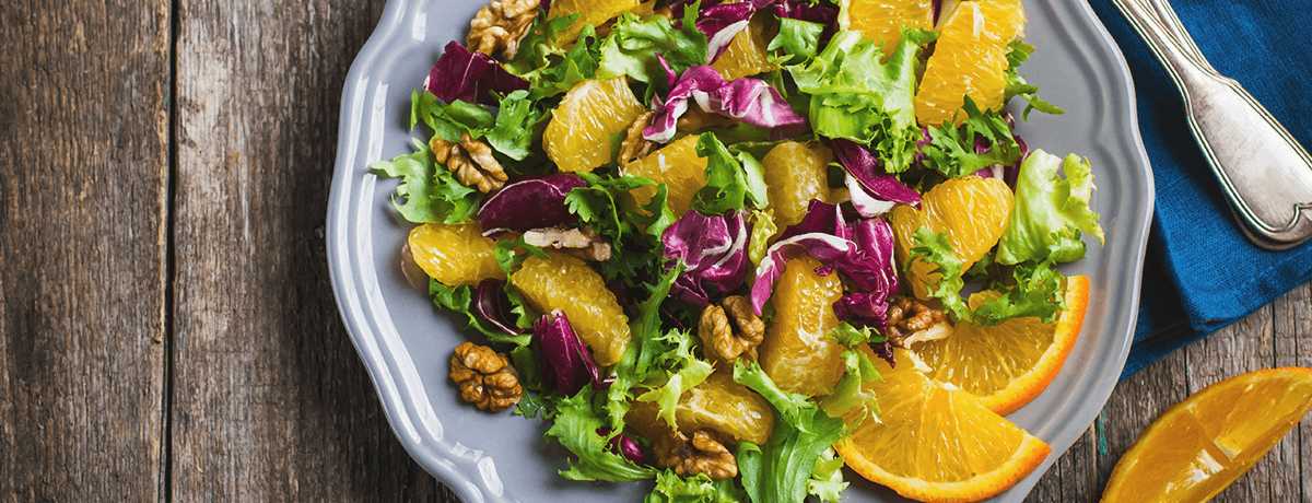 A photo of a bright salad mixing lettuce, citrus fruits, purple radicchio and walnuts. Click for the recipe. 