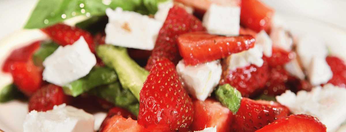 A close-up photo of a bright red, white, and green asparagus salad with feta cheese cubes