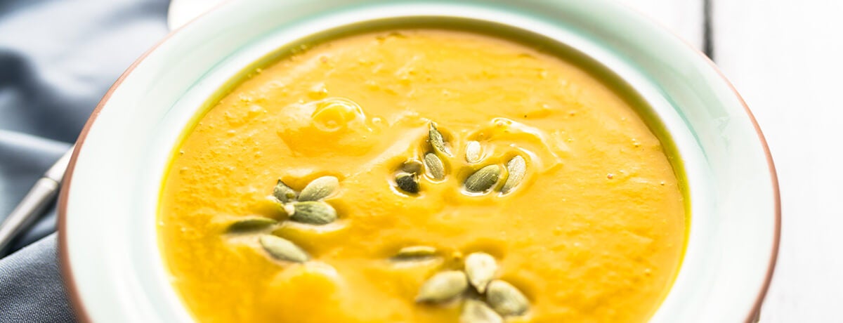 A bowl of raw vegan pumpkin soup topped with pumpkin seeds