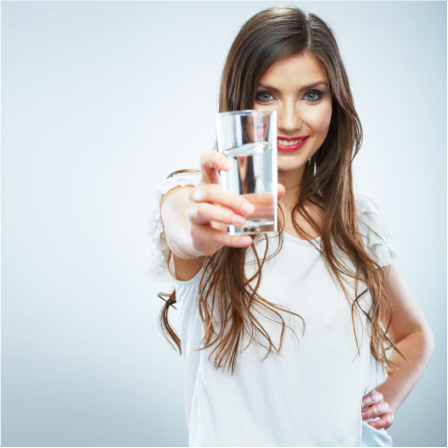 Frau hält ein Glas Wasser in die Kamera.