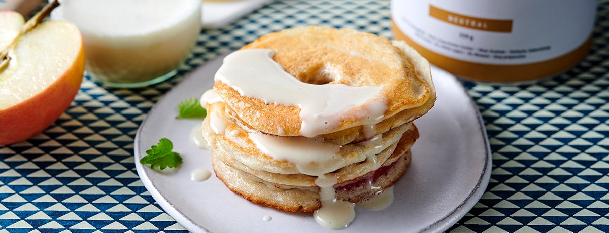 a stack of battered apple rings drizzled with creamy white vanilla sauce