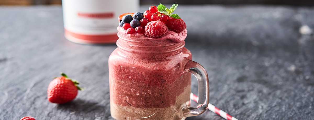 A chocolate berry shake in a Mason jar topped with fresh and bright berries