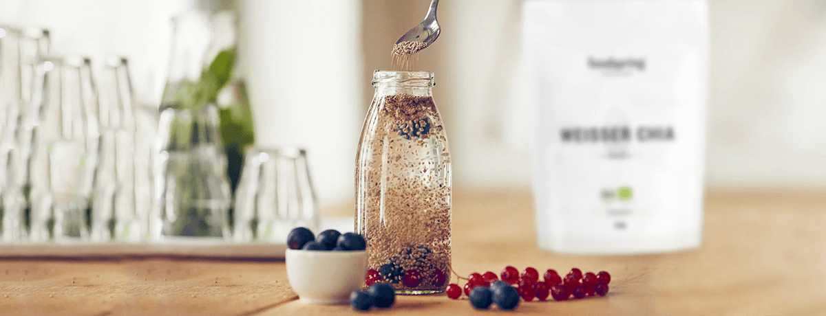 a photo of a bottle filled with chia seed lemonade surrounded by fresh blueberries and raspberries