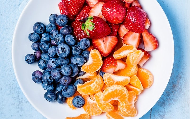 a bowl with bright blueberries, strawberries, and clementine segments