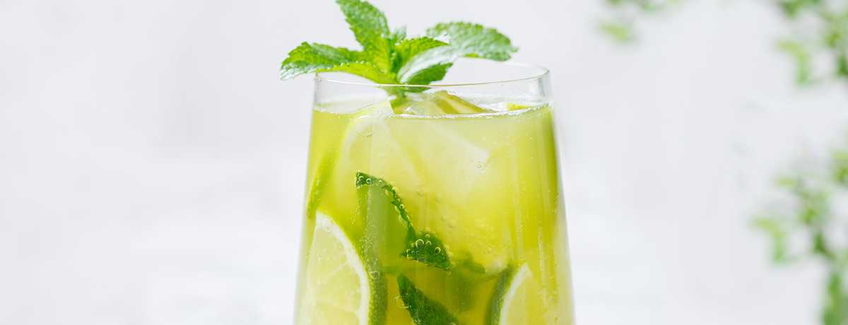 a wine glass of iced green tea with mint or other herbs, plus a wedge of lime, for a refreshing summer treat