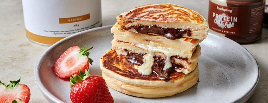 a stack of Protein Pancakes dripping melted Protein Cream 