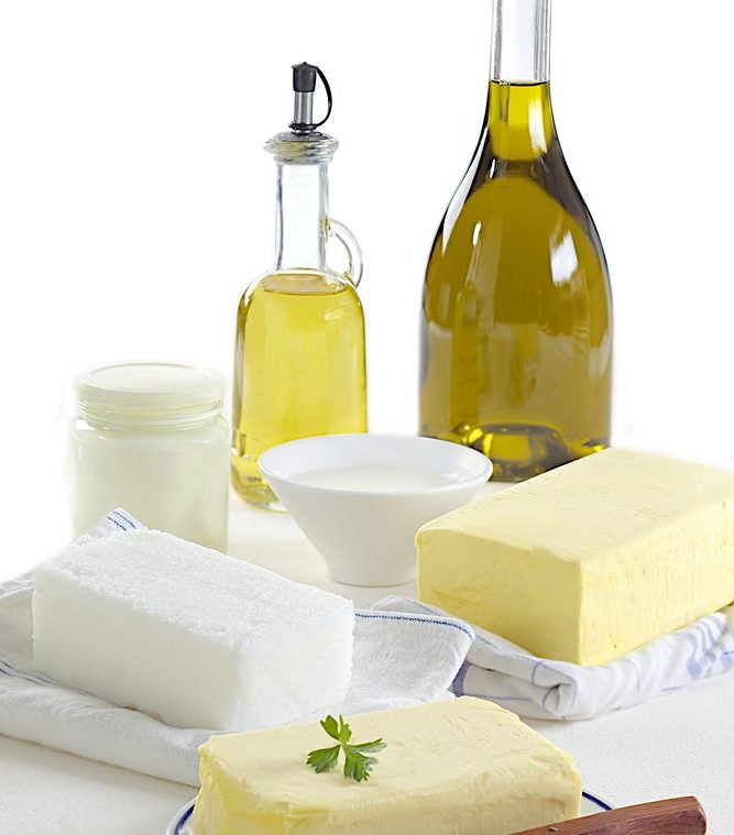 Eine Auswahl fettreicher Lebensmittel mit Butter, Öl, Käse und Milch.