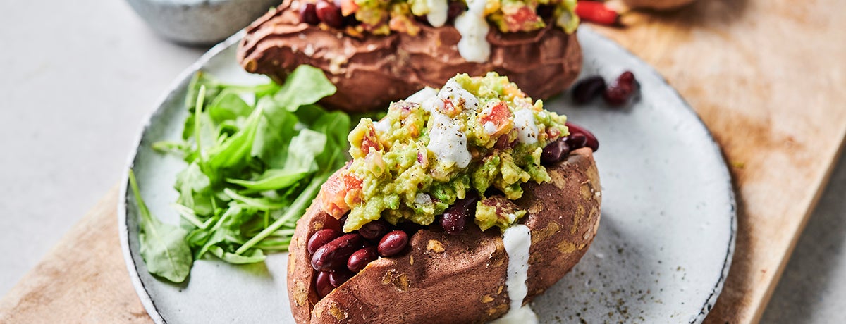 a stuffed baked sweet potato filled with kidney beans and guacamole