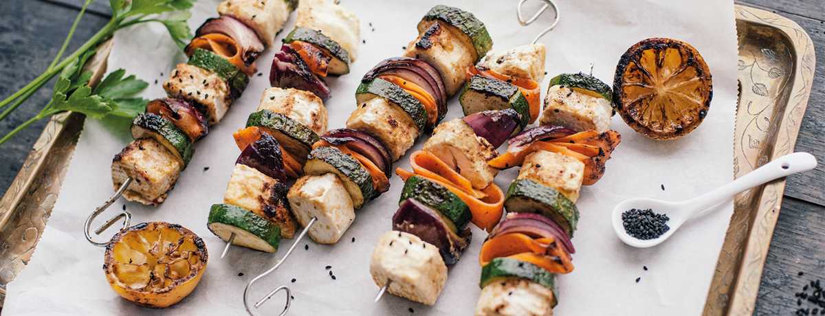 Skewers with colorful vegetables and cubes of feta cheese lined with and sprinkled with black pepper