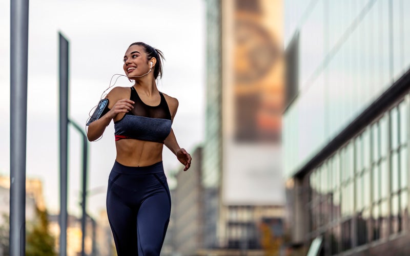 Frau joggt mit Sport BH durch eine Stadt