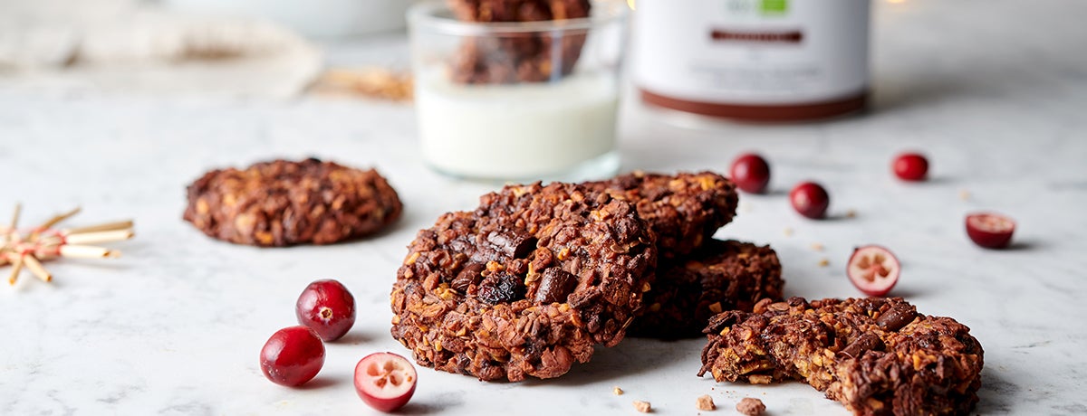 3-Ingredient Chocolate Cookies in a stack next to a few fresh cranberries, some whole and some expertly halved.