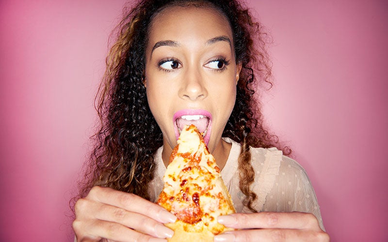 Frau beißt in ein Pizza Stück