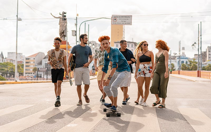Ein Mann fährt Skateboard, während hinter ihm eine Gruppe von Menschen läuft