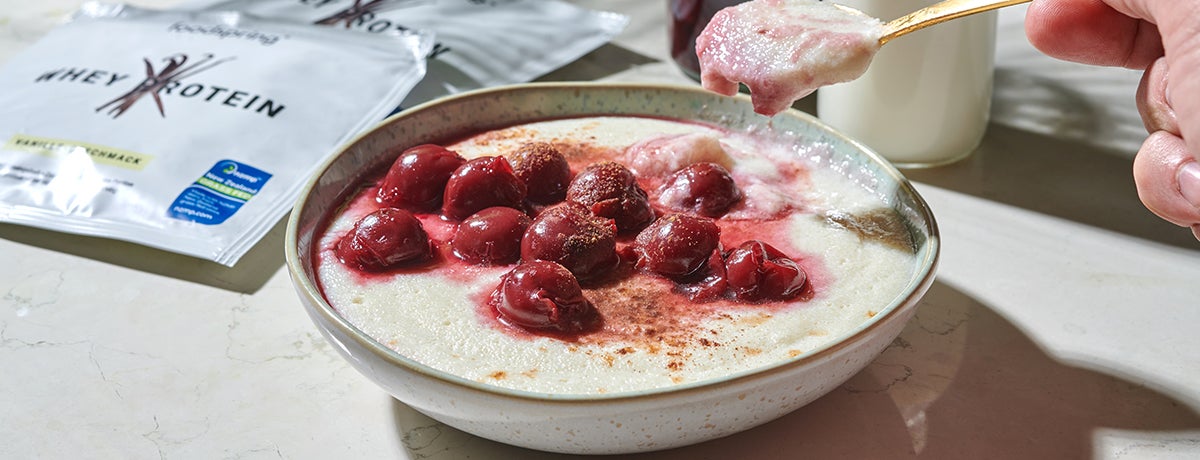 A bowl of protein semolina pudding topped with sweet jarred cherries and cinnamon