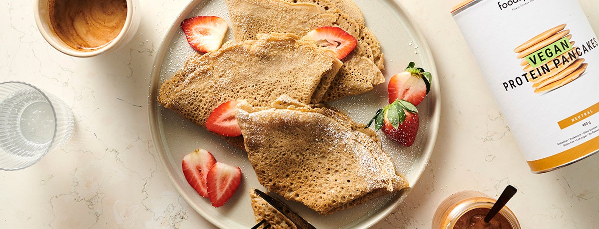 A beige plate holds vegan protein crepes with strawberries