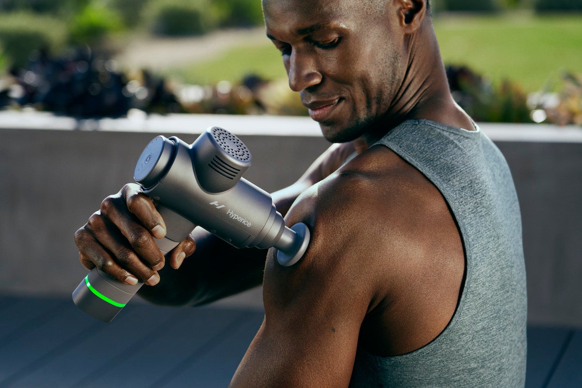 Homme utilisant un pistolet de massage sur les muscles des épaules.