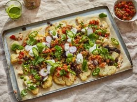 a tray with cauliflower nachos, a bowl of tomato salsa and a glass of coriander dressing
