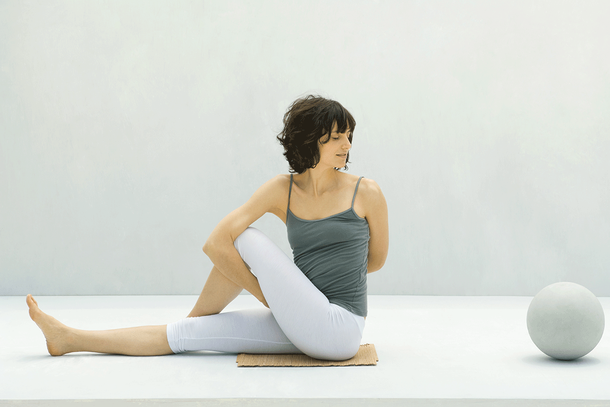 Frau sitzt in Yoga-Pose Drehsitz