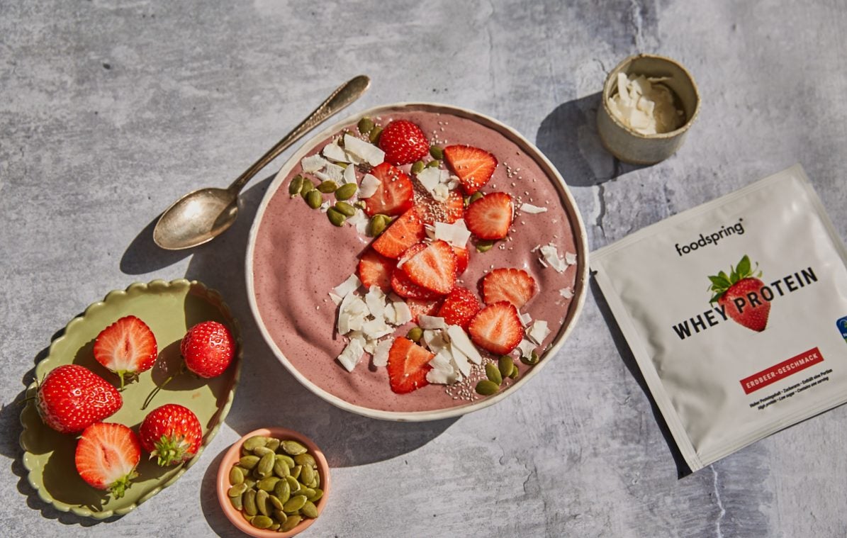 strawberry protein acai bowl with coconut pumpkin seed topping