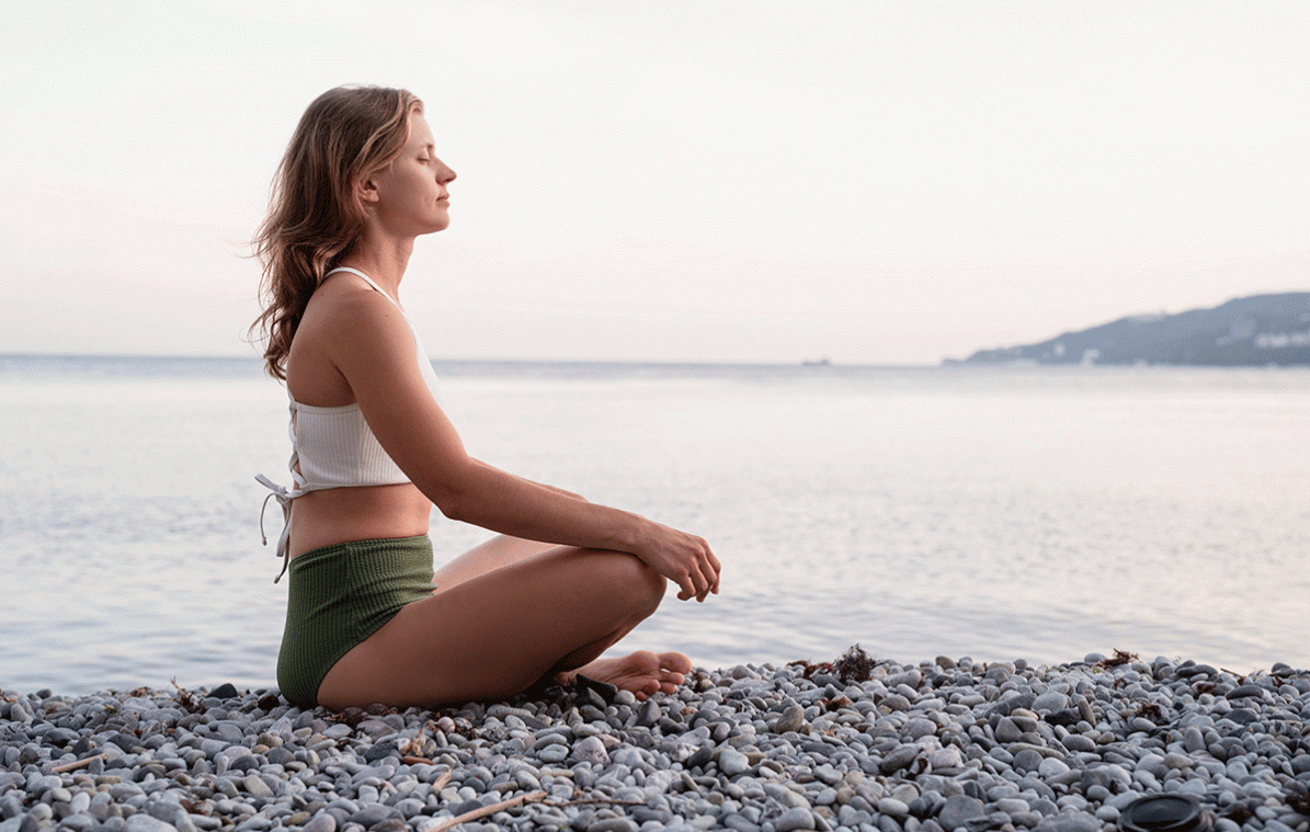 Frau meditiert am Strand