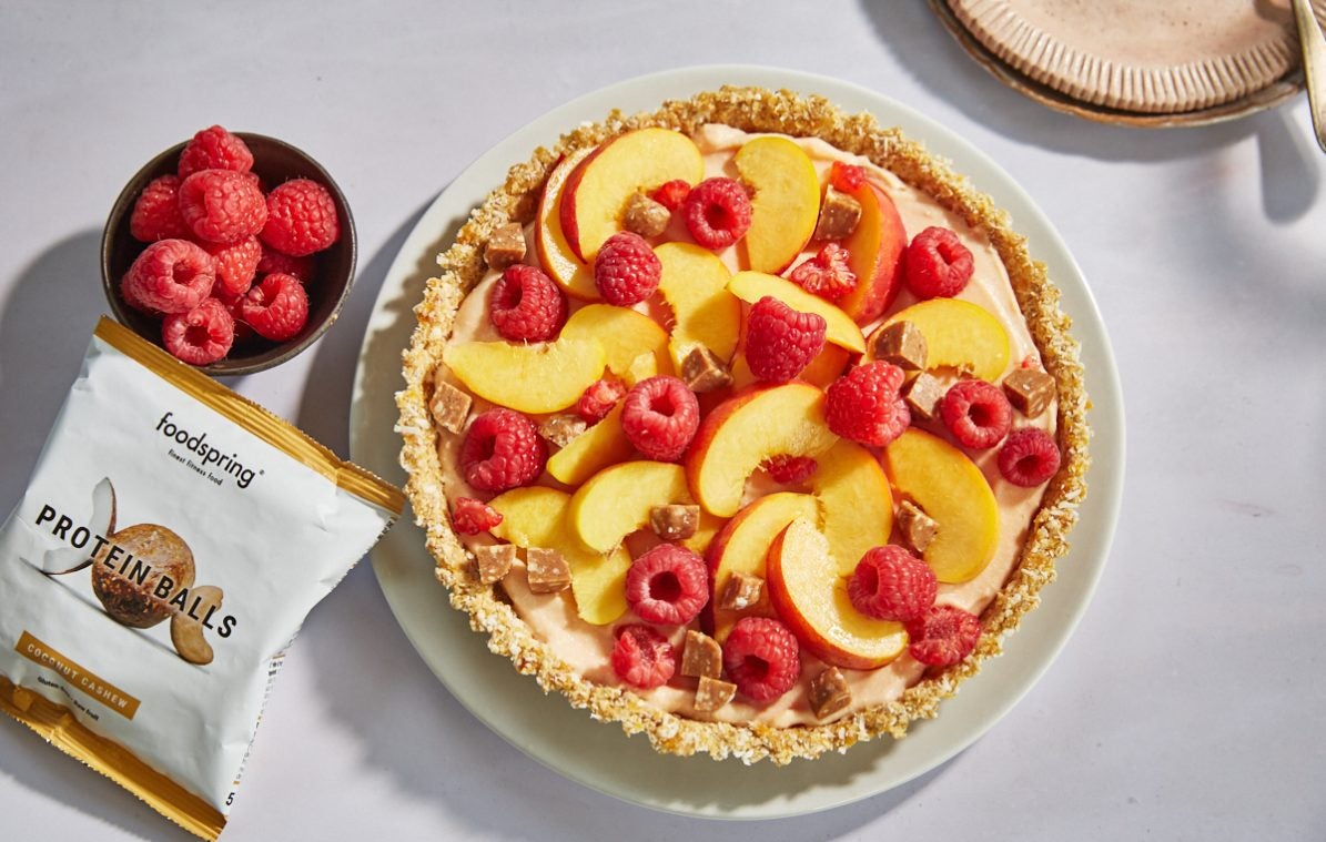 no bake peach and raspberry tart on a plate with bowl of raspberries
