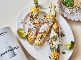 Mexican street corn on a plate with coriander and cheese
