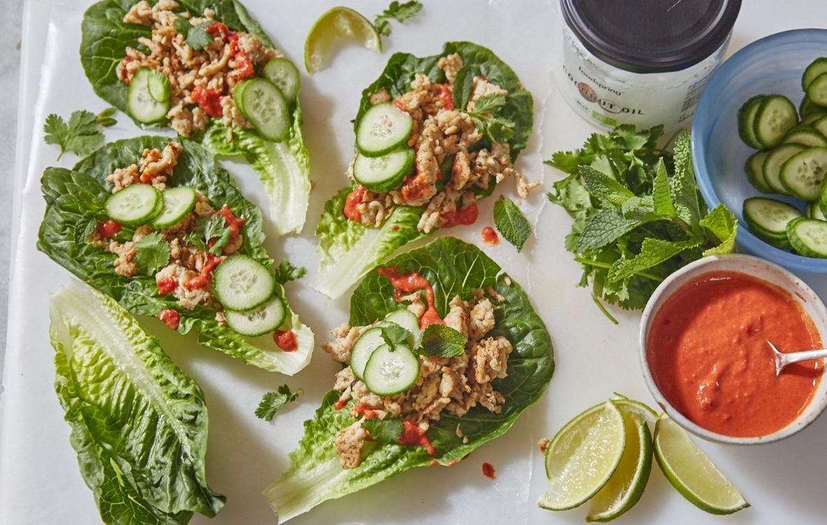 thai style chicken lettuce wraps with sweet chilli sauce on a cutting board with cucumber