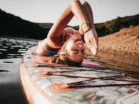 Frau macht Yoga auf Stand Up Paddle