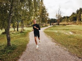 Björn Koreman sprints through the woods wearing all blac