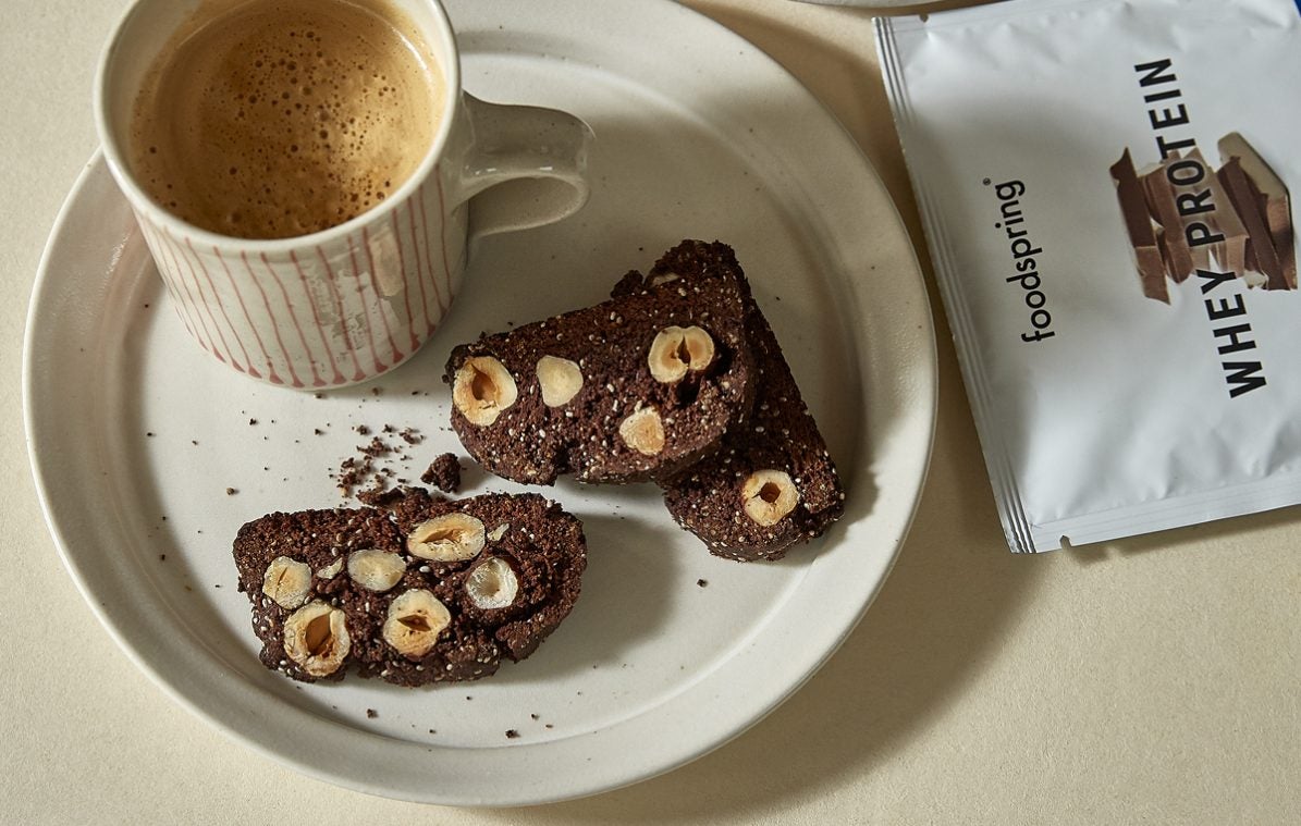 chocolate hazelnut protein biscotti on a plate with a cup of coffee