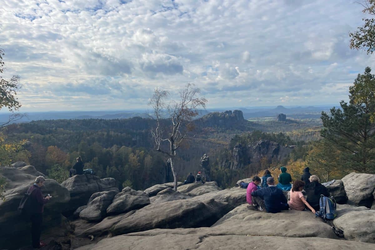 Persone sedute sulla roccia davanti a un paesaggio boschivo
